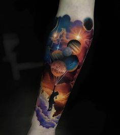 a man's arm with an image of planets and a person holding a balloon