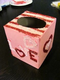 a pink box with glitter on it sitting on a table next to plates and forks