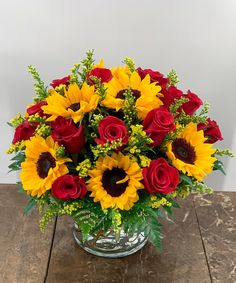 a vase filled with red roses and yellow sunflowers