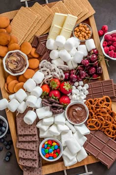 a platter filled with marshmallows, pretzels, fruit and chocolate