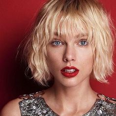 a woman with blonde hair and blue eyes wearing red lipstick is looking at the camera