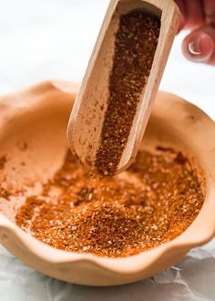 a wooden spoon scooping spices into a bowl