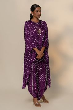 Purple full sleeves gajji silk high low kurta with all over quad bandhani motif pattern and cowrie shells embellishments at the centre. Paired with a matching overlapped dhoti skirt. - Aza Fashions Navratri Silk Bandhani Print Palazzo Set, Silk Bandhani Print Straight Kurta, Festive Long Sleeve Salwar Kameez With Bandhani Print, Festive Bandhani Print Salwar Kameez, Silk Bandhani Print Kurta For Navratri, Long Sleeve Bandhani Print Dress For Diwali, Silk Bandhani Print Palazzo Set For Navratri, Semi-stitched Long Sleeve Bandhani Kurta, Semi-stitched Long Sleeve Kurta With Bandhani Print