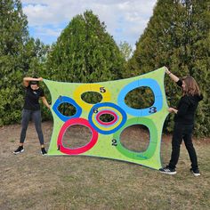 two people standing in front of a large kite with circles on it and numbers painted on the side