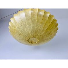 a yellow glass bowl sitting on top of a white table next to a light fixture