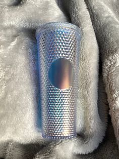 a silver cup sitting on top of a fur covered blanket