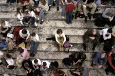 a group of people sitting on the steps in front of some stairs with one person holding a cell phone