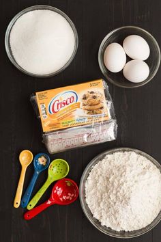 ingredients to make cookies laid out on a wooden table including flour, eggs and sugar