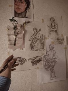 someone holding their hand up to some drawings on the wall