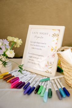 a table topped with lots of crayons next to a basket filled with flowers