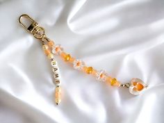 an orange and white beaded keychain laying on top of a white sheet