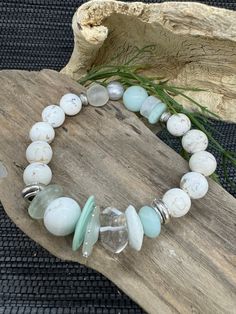 This unique "Tranquil Harmony: Handcrafted Cream Howlite, Aquamarine, and African Recycled Glass Beaded Bracelet with Antiqued Silver Accents" is a stunning blend of natural gemstones and mixed beads, creating a one-of-a-kind piece that complements any outfit. The antiqued silver accents add a touch of elegance, making it a perfect accessory for any occasion. Each bead is carefully selected and handcrafted with attention to detail, ensuring a unique and high-quality piece. Materials: Cream Howlite, Aquamarine, African Recycled Glass, Crystal Quartz, Freshwater Pearl, Lampwork Discs, Antiqued Silver-tone beads. Features: Natural Stones: High-quality Cream Howlite and Aquamarine gemstones, known for their calming and soothing properties. African Recycled Glass: Adds elegance and a touch of c Bohemian White Crystal Bracelet With Natural Stones, Bohemian White Round Crystal Bracelet, White Bohemian Crystal Bracelet Hand Wrapped, Bohemian White Crystal Bracelet Hand Wrapped, White Bohemian Hand Wrapped Crystal Bracelet, Bohemian White Hand Wrapped Crystal Bracelet, White Round Bohemian Stretch Bracelet, White Bohemian Stretch Bracelet, Bohemian White Crystal Bracelet With Faceted Beads