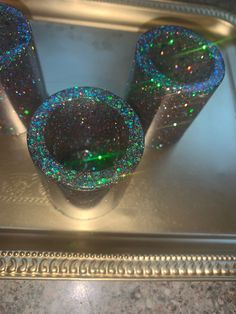 three glitter cups sitting on top of a metal tray