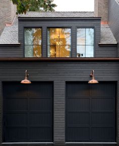 two black garage doors in front of a house