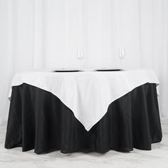 a table with two wine glasses on it and a white table cloth over the top