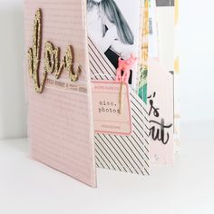 a pink photo album with gold glitter letters and photos on the front, along with a clipboard that says love