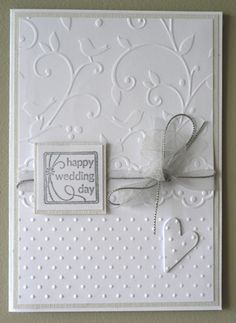 a wedding card with a bow and ribbon on the front, attached to a wall