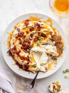 a white plate topped with mashed potatoes covered in bacon and cheese next to a glass of beer