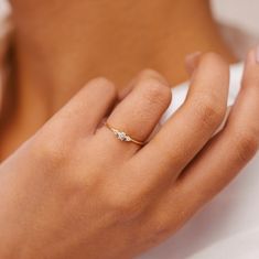 a woman's hand wearing a gold ring with three small diamonds on the band