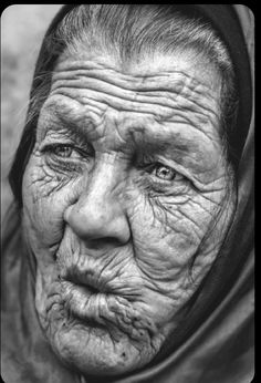 an old woman with wrinkles on her face and headdress, looking at the camera