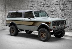 an off road vehicle parked in front of a stone wall