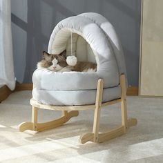 a cat is laying in a small bed on the floor next to a rocking chair