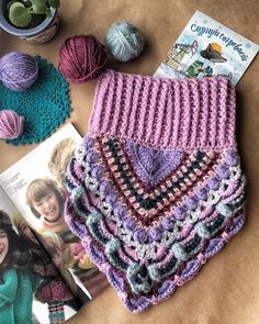 crocheted afghans and magazines on a table with yarn, knitting needles and other items