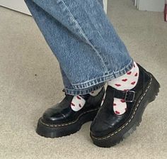 a person wearing black and white socks with red hearts on them, standing in front of a door