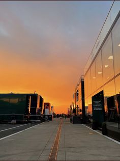 the sun is setting on an empty street in front of a building with glass walls