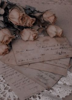 some old papers and flowers on a lace doily