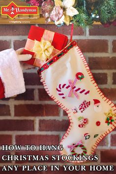 a person holding a christmas stocking in front of a fire place with stockings hanging from it