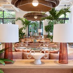 a large room filled with lots of tables and chairs next to tall planters in front of windows