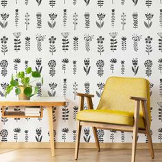 two chairs and a table in front of a wall with black flowers on the wall