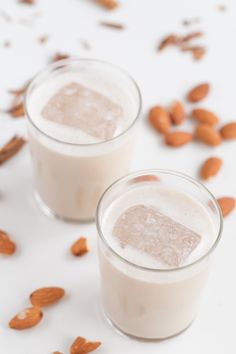 two glasses filled with almond milk on top of a table