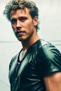 a man with curly hair wearing a black leather shirt and looking at the camera while standing in front of a white wall