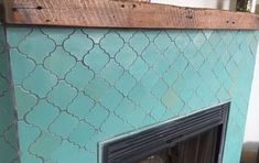 a fireplace with a wooden mantle and blue tile