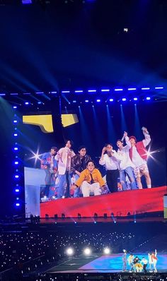 a group of people standing on top of a red and blue stage in front of a crowd