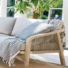 a white couch sitting on top of a wooden floor next to a potted plant