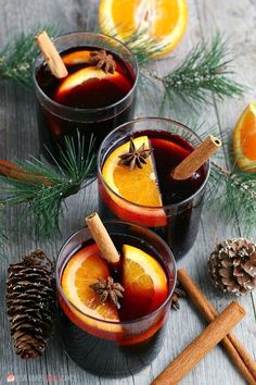 two glasses filled with mulled and topped with orange slices, cinnamon sticks and star anise