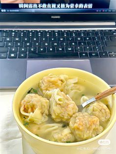 a yellow bowl filled with dumplings next to a laptop