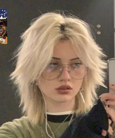 a woman with blonde hair and glasses taking a selfie in front of a mirror