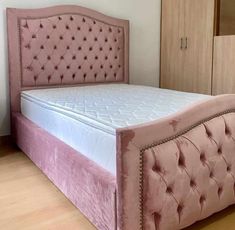 a bed with pink velvet upholstered headboard and foot board