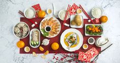 a table topped with plates and bowls filled with different types of food next to oranges