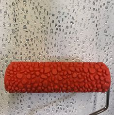 a close up of a red object on a metal rack with water drops all over it