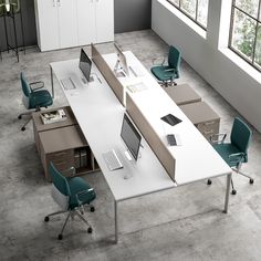 an office desk with two laptops on it and three chairs around it, in front of a large window