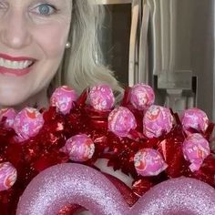 a woman holding up a pink heart shaped balloon in front of her face and smiling at the camera