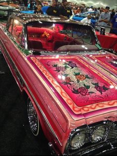 an old pink car is on display at a car show