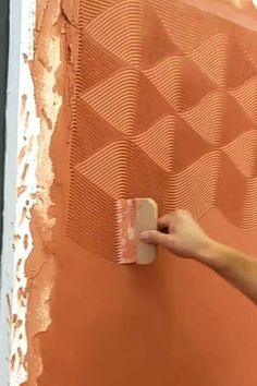 a person painting a wall with orange paint