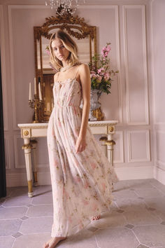 a woman standing in front of a mirror wearing a dress with floral print on it