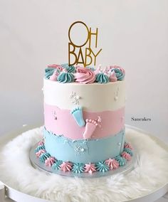 there is a cake with pink, blue and white frosting on the top that says oh baby